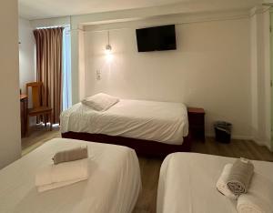 桑斯HAVANA Hôtel的酒店客房设有两张床和一台平面电视。