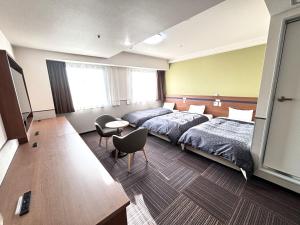 仓敷仓敷市1-2-3酒店的酒店客房带两张床和一张桌子以及椅子。