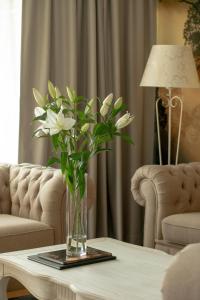 米泽德沃兹Juvena Hotel Wellness & SPA的客厅桌子上的白花花瓶