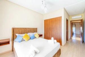 马拉喀什Chez taux的一间卧室配有白色的床和蓝色和黄色枕头