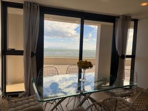 斯特兰德Loddey's Self Catering Apartments - by Beach Collection的一间设有玻璃桌并享有海滩美景的用餐室