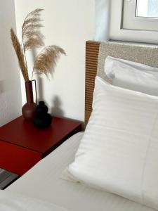 希俄斯MYROVOLOS APARTMENTS的一张铺有白色床单的床和一张红色桌子上的花瓶