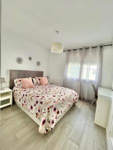 贝纳尔马德纳Tulipanes Benalmádena - Parking privado的白色卧室配有带粉红色枕头的大床
