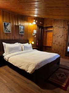 培拉特曼加勒米酒店的一间卧室配有一张带木墙的大床