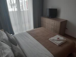 布拉索夫Apartament Marcel - Coresi Mall的一间卧室配有一张床,梳妆台上配有电视