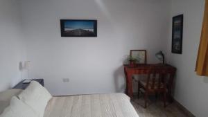 拉普拉塔Departamento tranquilo y luminoso的一间卧室配有一张床和一张桌子,墙上挂着一张照片