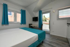 斯图加特City-Hotel Zuffenhausen的一间卧室配有一张蓝色窗帘的床和一个阳台