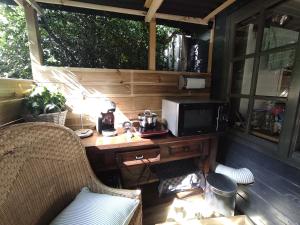皮滕"Tempat Senang" chalet on the beautiful Veluwe with airco sauna bbq jacuzzi beamer and dog的门廊上的一张桌子、一台微波炉和一台电视