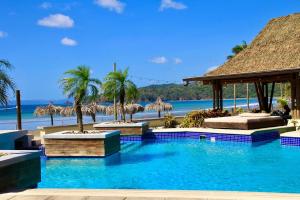 普拉纳维瑙Nearly Oceanfront Blue 3 Bedroom Spacious Villa的棕榈树和海滩度假村的游泳池