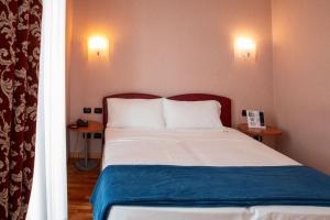 多尔梅莱托SIRIOHotel的一间卧室配有一张带两张桌子和两盏灯的床。