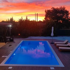 克拉法吉亚Drosoula Villa 3bdr private swimming pool的蓝色的游泳池,背景是日落