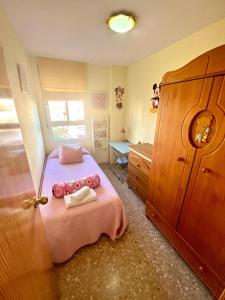 卡耐特蒂贝兰格Apartamento en la Playa Canet, muy cerca de Valencia的一间小卧室,配有粉红色的床和一张书桌