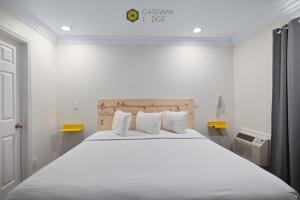 滨海城Gateway Lodge的卧室配有一张带白色床单和枕头的大床。