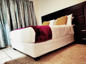 姆巴巴内Apartment on MR103的一间卧室配有一张白色的床和黑色床头板