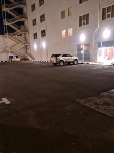 Al Fayşalīyahفندق روزميلون的停在大楼旁边的停车场的汽车
