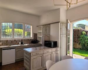 胡安莱潘Juan les pins : Villa de charme avec piscine的厨房配有白色橱柜和桌椅