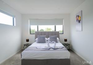 奥克兰Modern Howick Town House Fibre WiFi Netflix的卧室的床上有两条天鹅绒毛巾