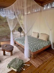 莫雷雷Casa Maiara (Eco friendly)的一间卧室配有一张带窗帘和桌子的床