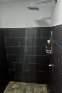 PoásEpimoni的浴室铺有黑色瓷砖,配有淋浴。