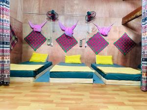 Làng CacDu Gia Field View Homestay的客房设有三张床和粉色及黄色枕头。