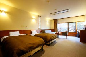 阿苏市Hotel Aso No Tsukasa的酒店客房配有两张床和一张书桌