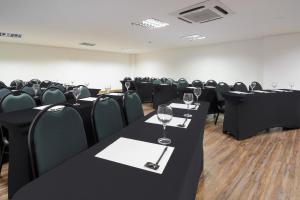 劳鲁-迪弗雷塔斯萨尔瓦多机场城际酒店的一间会议室,配有黑色桌椅和酒杯