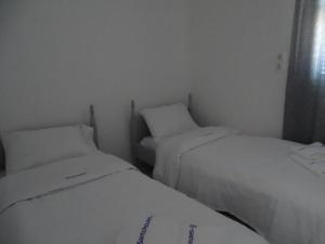 莫诺利索斯Splendid Santorini Villa | Bella Beach House | 3 Bedrooms | Private Terrace and Beautiful Sea Views | Monolithos的小客房内的两张床,配有白色床单