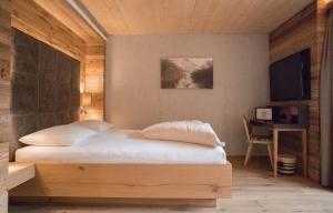 沙特瓦尔德Ruhehotel & Naturresort Rehbach - Adults only的一间卧室配有一张带书桌和电视的床。