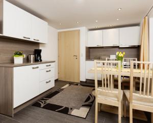 因青洛斯勒霍夫公寓的厨房配有白色橱柜和桌椅