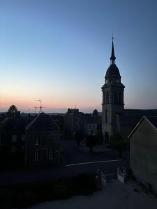 Lignieres-OrgeresMaison d'hôtes La Doucelle的黄昏时有一座教堂,塔楼有陡峭的陡峭