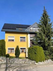 施瓦岑贝格Ferienwohnung Heike Strobel的屋顶上设有太阳能电池板的黄色房子