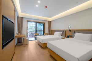 张家界Hunan New Pipaxi Hotel的酒店客房设有两张床和一台平面电视。