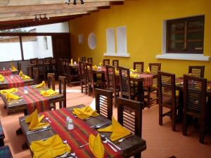 LassoHostería Hotel Cuello de Luna - Cotopaxi - Country Inn的餐厅设有木桌和黄餐巾