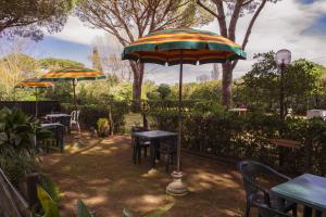格罗塞托港Area Sosta La Pampa的一个带桌椅和遮阳伞的庭院