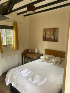 BramleyThe Wheatsheaf的一间卧室配有一张带白色床单的床和一张书桌。