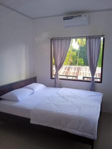 RiungRiung Tiga Empat Tujuh Guesthouse的卧室配有白色的床和窗户