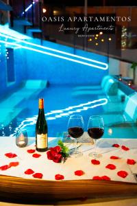 菲内斯特拉特APARTAMENTOS OASIS DE LA CALA的游泳池畔的桌子上放着两杯葡萄酒和玫瑰