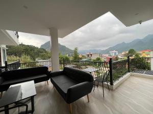 河江LiLa Inn & Motorbike Tours Ha Giang的带沙发的客厅和山景阳台。