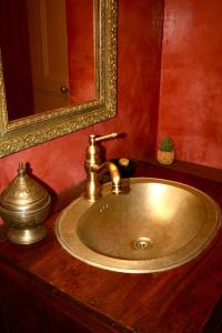 尼翁Le Clos des Laurons的浴室水槽设有金色水龙头和镜子