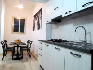 科米索Trinacria House - Appartamento Deluxe Comiso的厨房配有水槽和桌椅