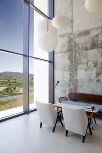 Entrena博德加芬卡洛斯阿迪诺斯酒店的一间设有白色椅子、桌子和大窗户的用餐室