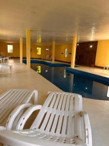 科隆Cabañas Altos de Artalaz的一座带白色长凳的游泳池