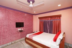 JādabpurOYO Flagship Rainbow Guest House的一间卧室配有一张床,墙上配有电视