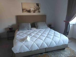 代因泽Appartamento confortevole的一张白色的大床,上面有一只白色填充物的动物