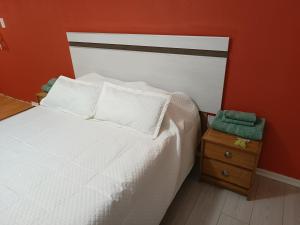 里瓦达维亚海军准将城Casa Catalina zona sur的一间卧室配有一张白色的床和橙色的墙壁