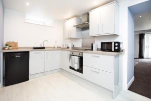 巴克斯顿Garden Apartment - Close to Town Centre - sleeps 6的白色的厨房,配有白色的橱柜和黑色的器具