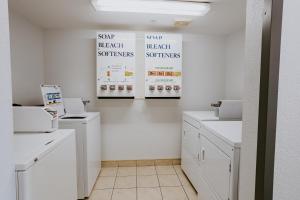 雷德迪尔Mosaic Suites的洗衣房配有白色橱柜和墙上的海报