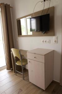 吉奥塔略克拉尼亚海边一室公寓酒店的一间设有一张桌子和一把椅子的房间,墙上设有一台电视机