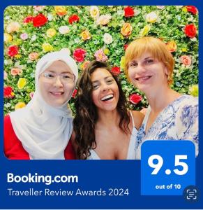 迪拜Dreams beach hostel的三个女人站在鲜花墙前