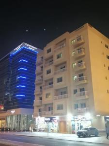 迪拜Pharaohs Inn MOE Hostel的前面有停车位的建筑